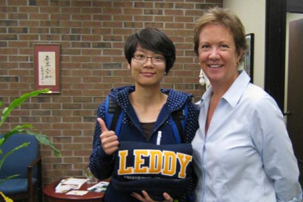 Xi Yan receives a sweatshirt and congratulations from associate dean of the library Joan Dalton.