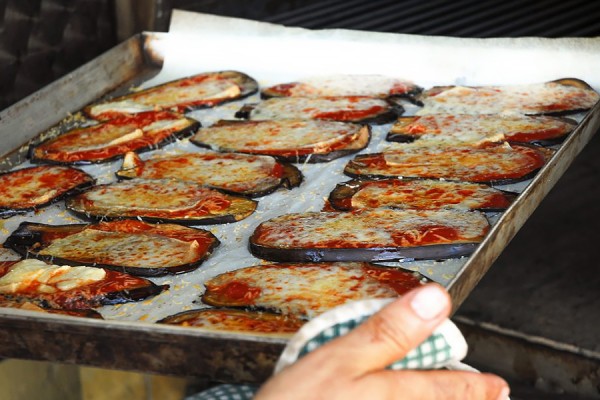 cook removing sheet tray of eggplant cutlets from oven