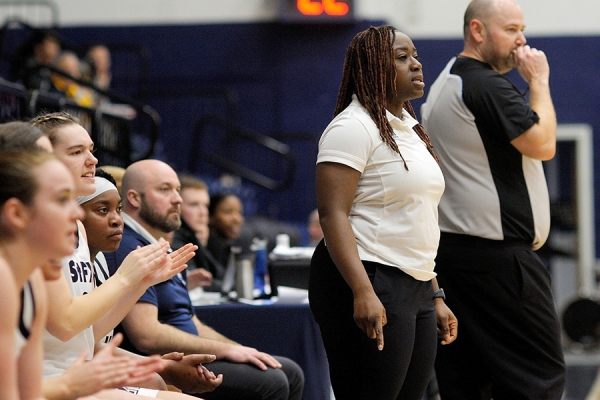 Lee Anna Osei standing before players bench at St. FX