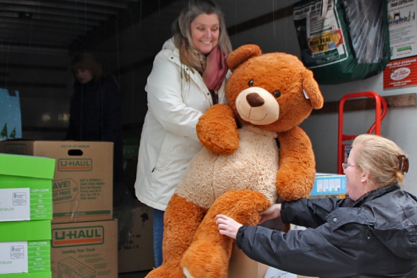 Volunteers load large stuffed teddy bear into truck