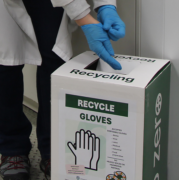 gloves being placed in recycling bin